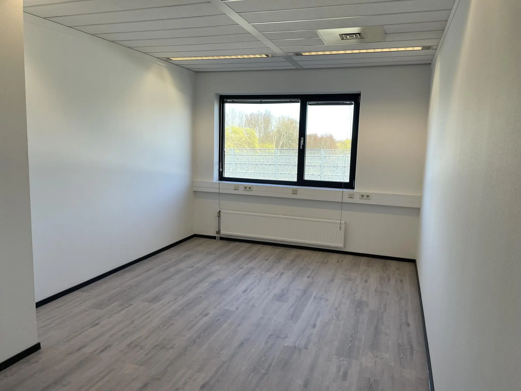 Lege, lichte kantoorruimte met raam aan de Laan van s‑Gravenmade.